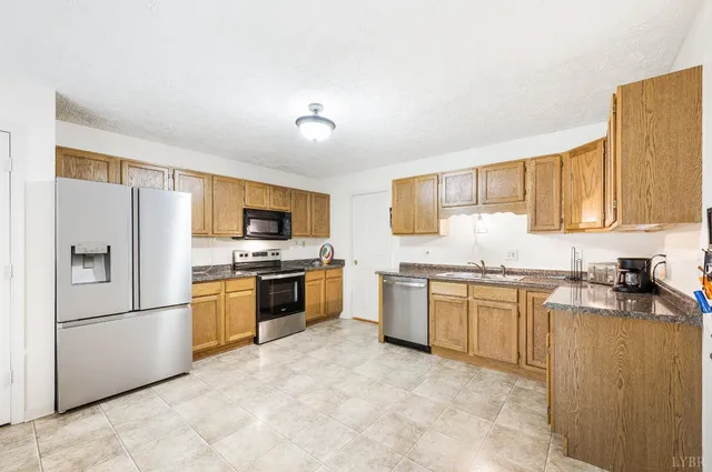 a kitchen with granite countertop a refrigerator stove top oven and sink