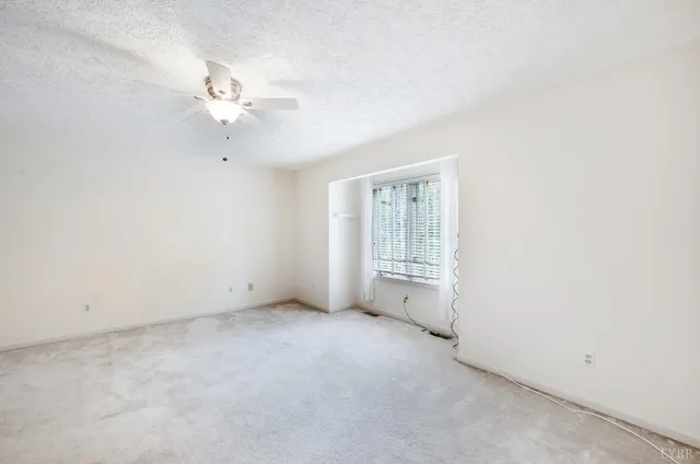an empty room with a window and a ceiling fan