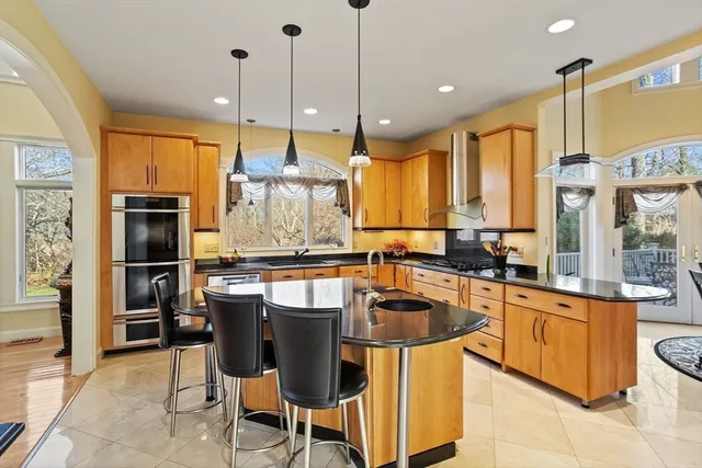 a kitchen with stainless steel appliances granite countertop table chairs sink and cabinets