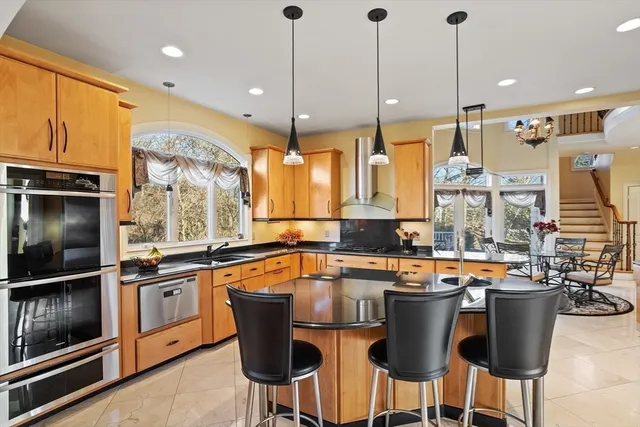 a kitchen with stainless steel appliances a stove a sink a oven a dining table and chairs