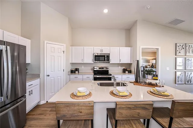 a kitchen with stainless steel appliances granite countertop a dining table and chairs