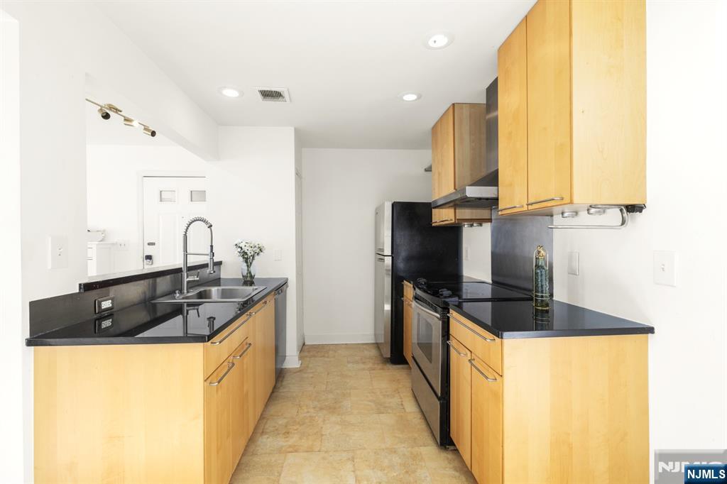 100 Crown Court, Unit 482 Edgewater, NJ 07020 - Photo 6 of 16 a kitchen with stainless steel appliances a sink and a refrigerator