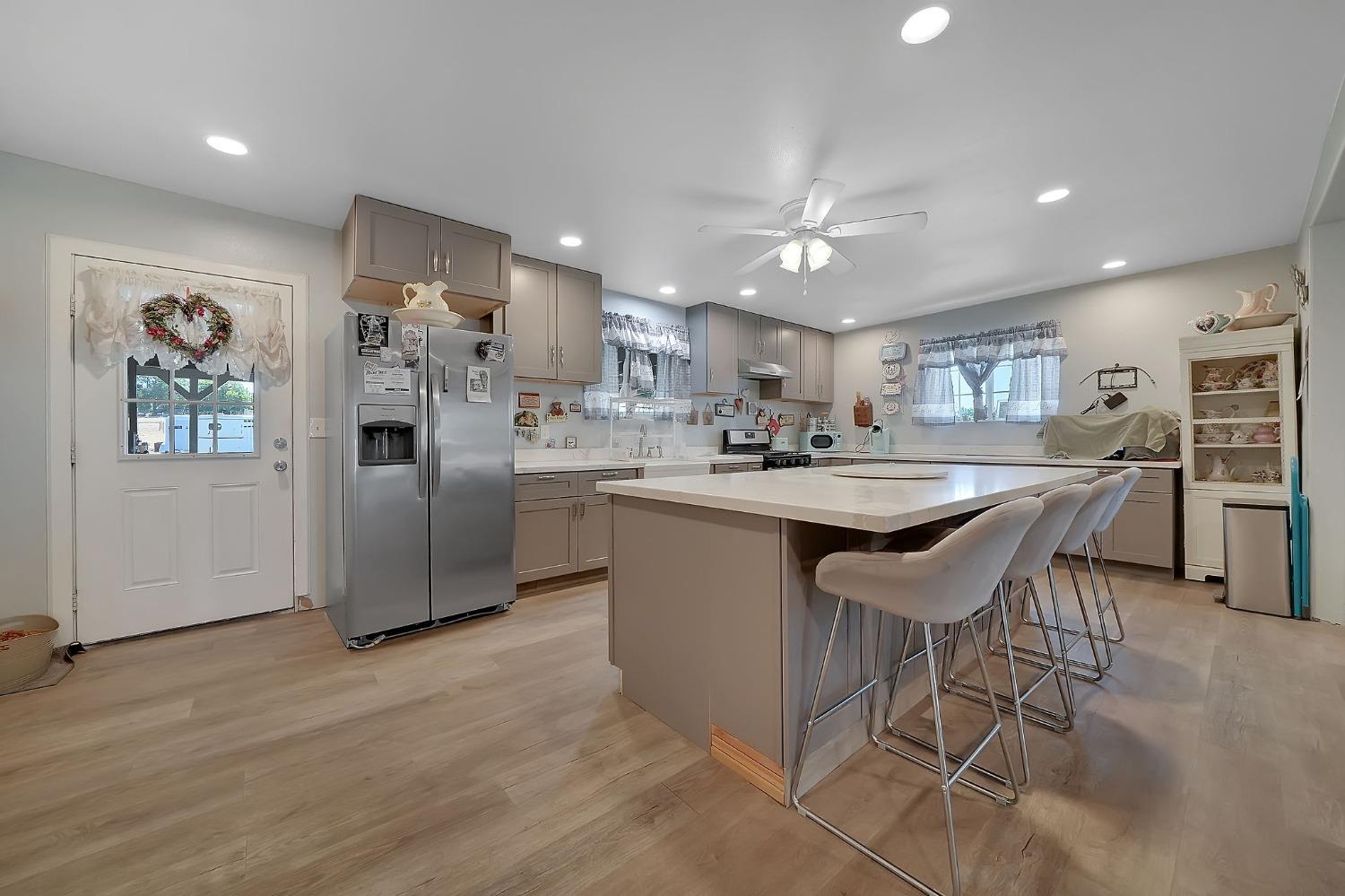 3585 South Burson Road Valley Springs, CA 95252 - Photo 51 of 99 a kitchen with stainless steel appliances kitchen island granite countertop a refrigerator a stove a sink a dining table and chairs with wooden floor