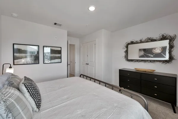 a bedroom with a bed and a mirror on the dresser