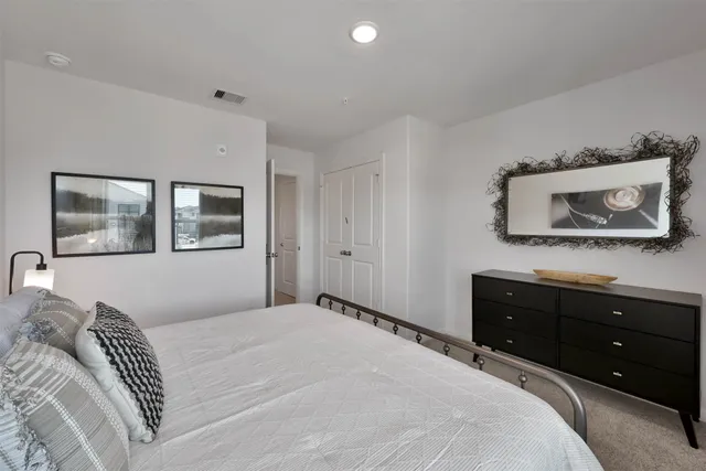 a bedroom with a bed and a mirror on the dresser