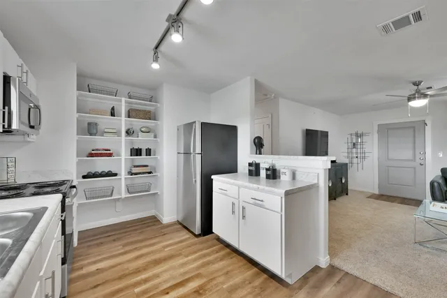 a kitchen that has a lot of white cabinets and stainless steel appliances