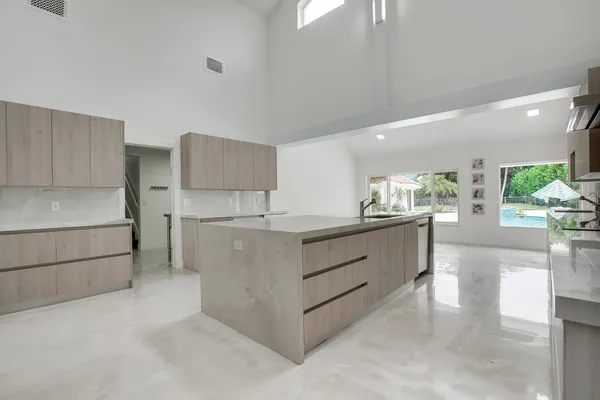 a large white kitchen with kitchen island a sink stainless steel appliances and cabinets