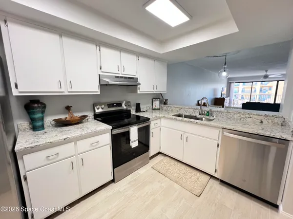a kitchen with granite countertop white cabinets white appliances and sink