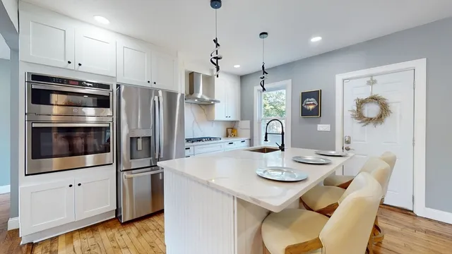 a kitchen with stainless steel appliances granite countertop a sink a stove a refrigerator cabinets and dining table