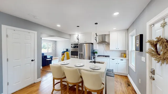 a kitchen with stainless steel appliances kitchen island granite countertop a refrigerator a sink a stove a dining table and chairs