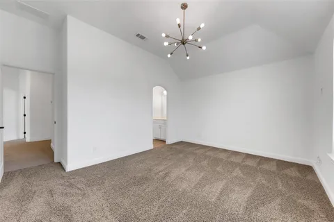 a view of an empty room with a chandelier fan