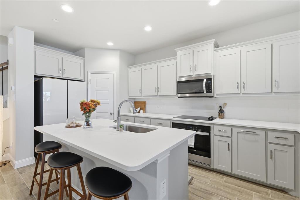 6092 Bursey Road Watauga, TX 76148 - Photo 2 of 23 a kitchen with a sink a stove a refrigerator and white cabinets with wooden floor