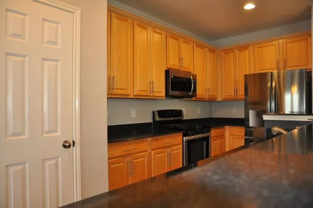 a kitchen with stainless steel appliances granite countertop a sink dishwasher a refrigerator and wooden floor