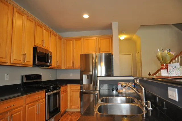 a kitchen with stainless steel appliances granite countertop a sink a stove and a refrigerator