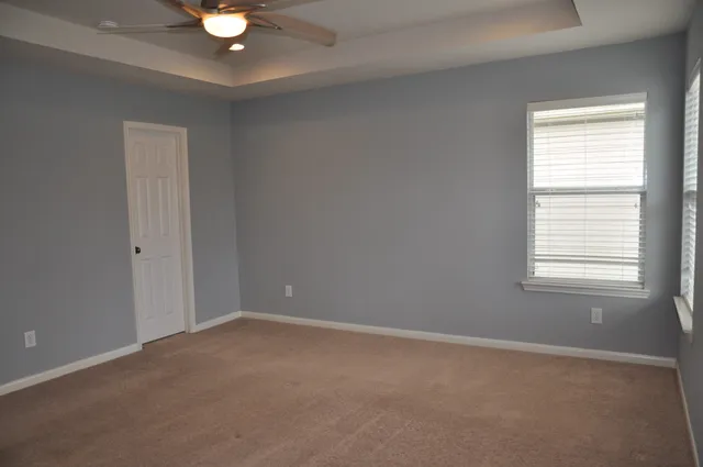 an empty room with a bathroom and a ceiling fan