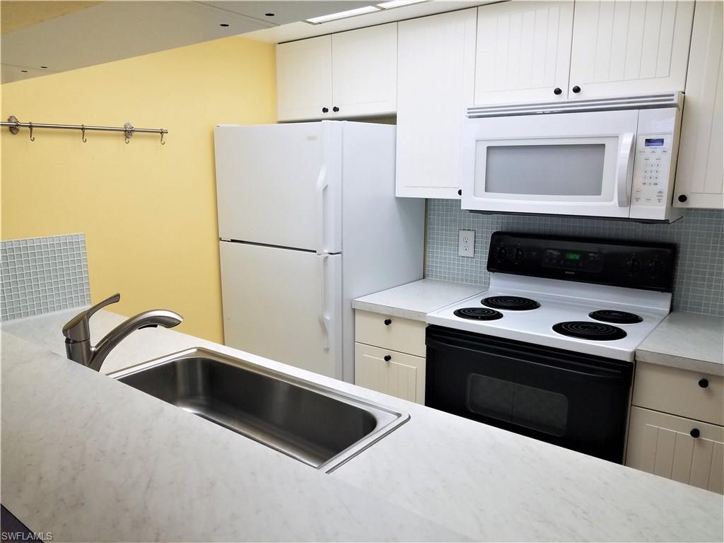 4363 27th Court Southwest, Unit 2103 Naples, FL 34116 - Photo 5 of 15 a kitchen with refrigerator a stove a sink and cabinets