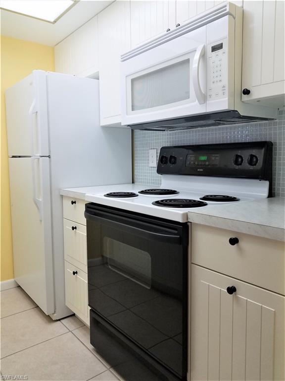 4363 27th Court Southwest, Unit 2103 Naples, FL 34116 - Photo 7 of 15 a kitchen with stainless steel appliances white cabinets and a stove