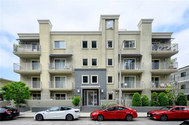 a front view of a residential apartment building with cars parked