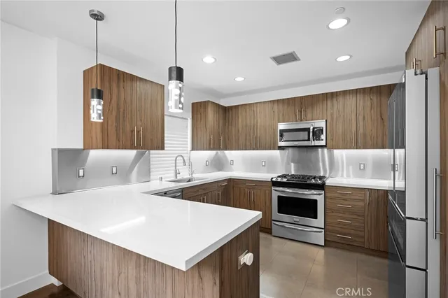 a kitchen with stainless steel appliances a stove a sink a refrigerator and cabinets