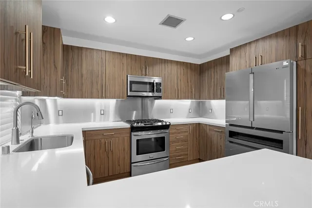 a kitchen with kitchen island a stove a sink and a refrigerator with wooden floor