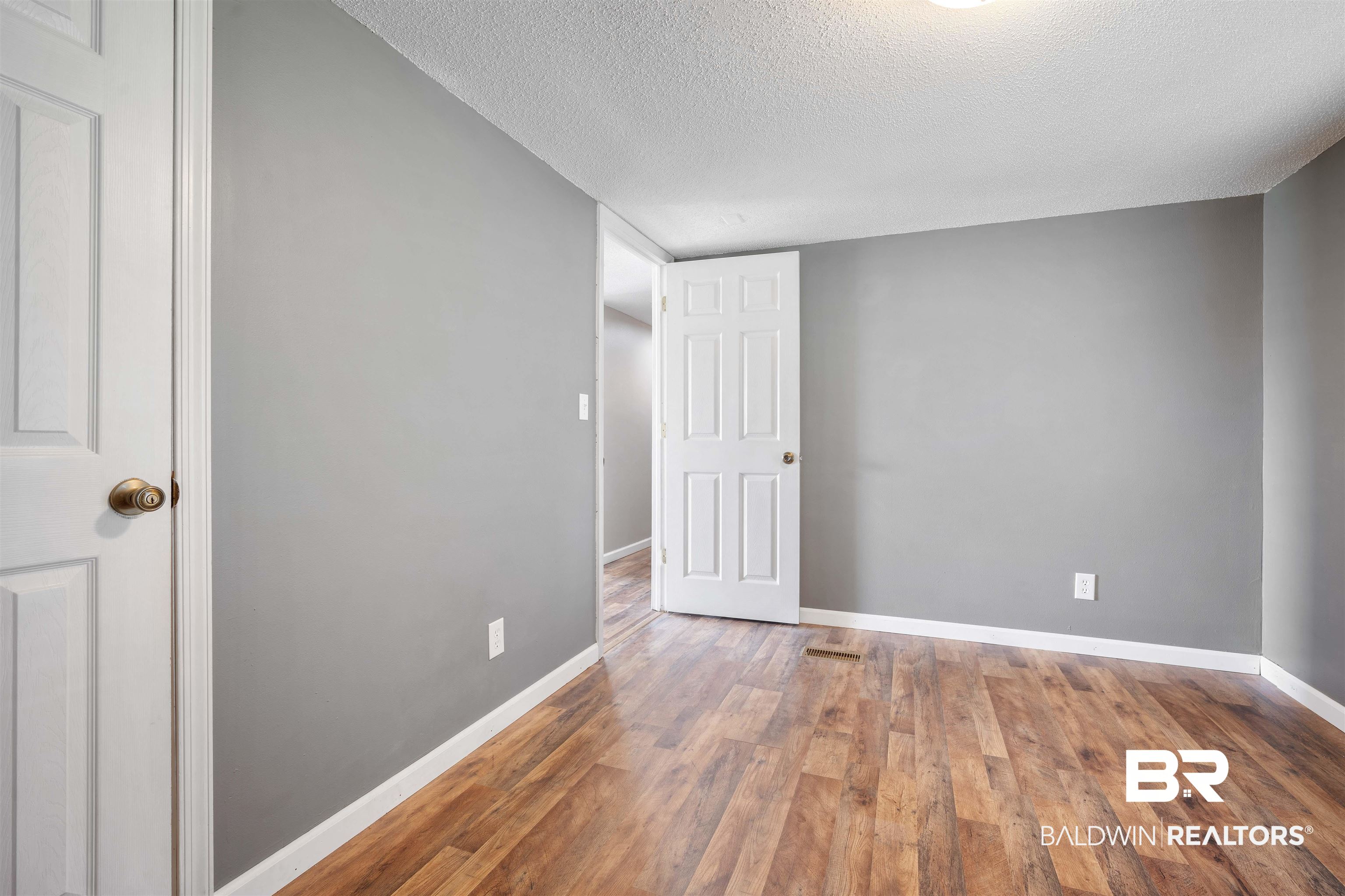 9011 Wilmer Georgetown Road Wilmer, AL 36587 - Photo 18 of 34 Spare room with baseboards, a textured ceiling, and wood-type flooring