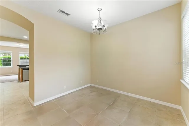 en empty room with windows and chandelier