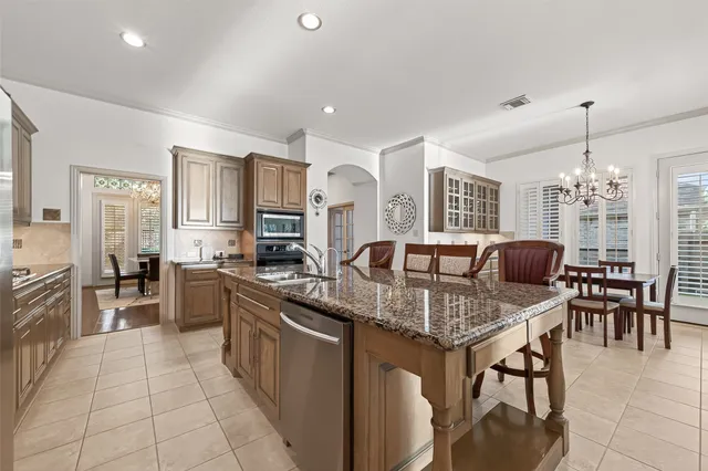 a kitchen with stainless steel appliances kitchen island granite countertop a table chairs microwave and sink