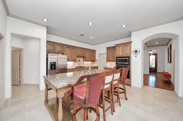 a kitchen with stainless steel appliances granite countertop a stove top oven a sink dishwasher a dining table and chairs with wooden floor