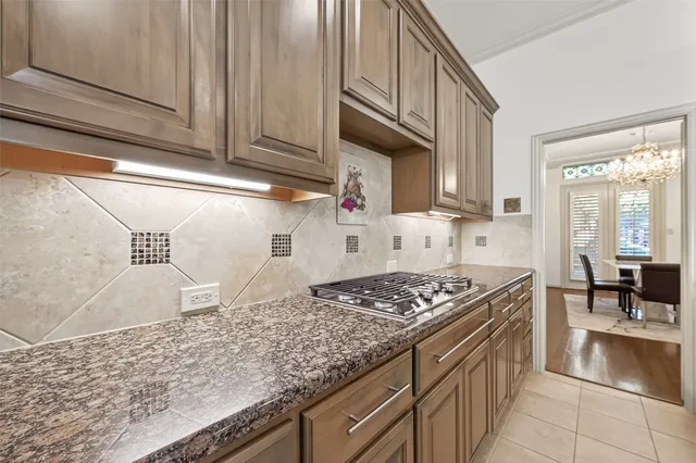 a dining area with stainless steel appliances kitchen island granite countertop a dining table chairs and a refrigerator