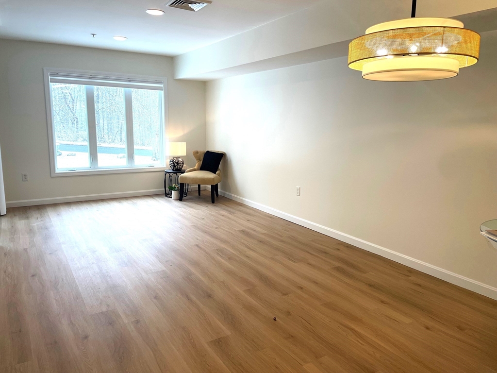 2 Duck Pond Road, Unit 108 Beverly, MA 01915 - Photo 2 of 17 a view of an empty room with a window and wooden floor