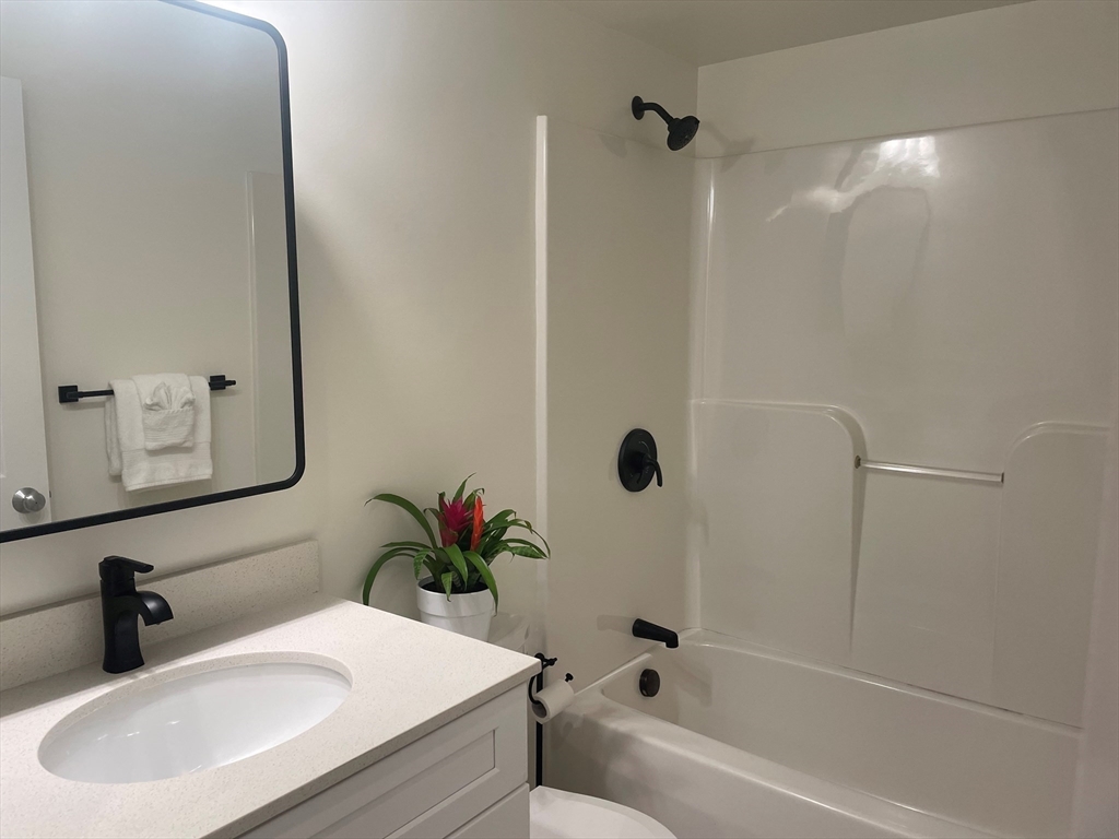 2 Duck Pond Road, Unit 108 Beverly, MA 01915 - Photo 5 of 17 a bathroom with a sink a mirror a potted plant and a bathtub