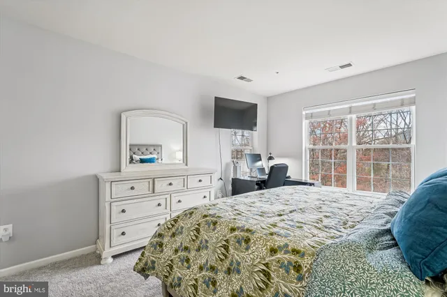 a bedroom with a large bed and a flat tv screen on dresser