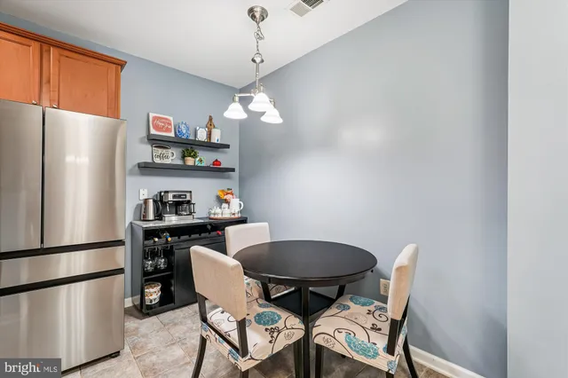 a kitchen with stainless steel appliances granite countertop a dining table chairs refrigerator and sink
