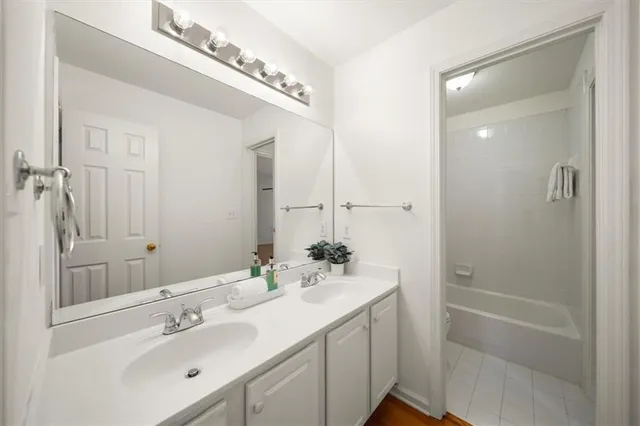 a bathroom with a bathtub shower sink vanity and mirror