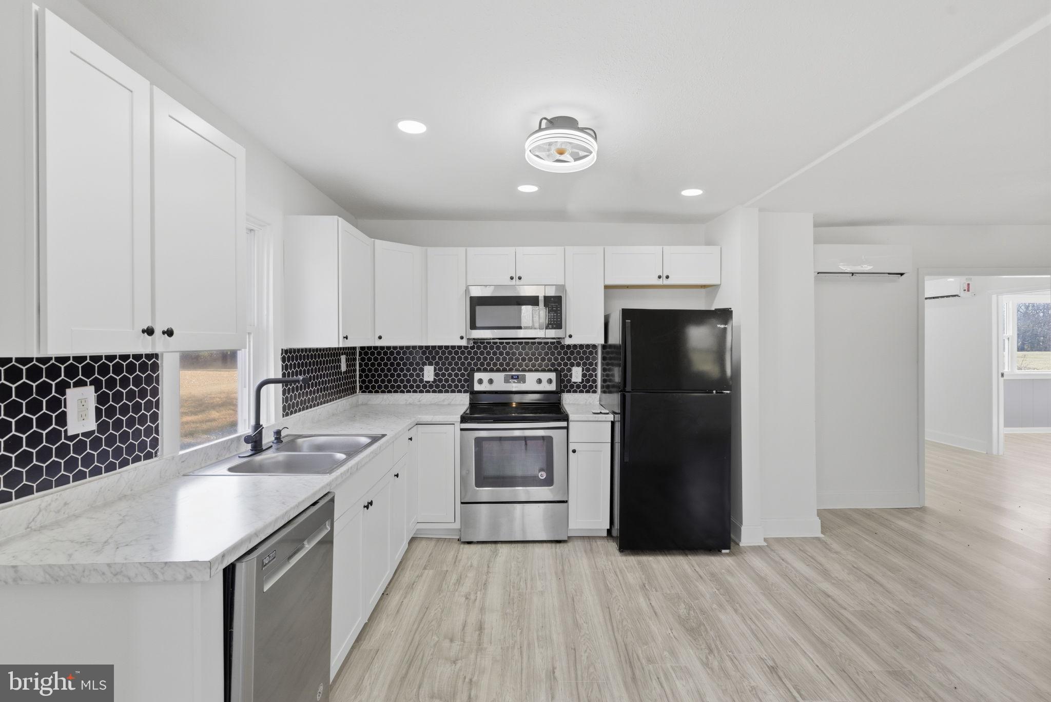 5020 Tucker Hill Road Hague, VA 22469 - Photo 13 of 31 a kitchen with a sink a refrigerator and a stove top oven with wooden floor