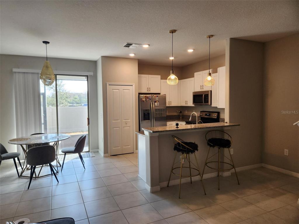 14350 Easy Goer Street Ruskin, FL 33573 - Photo 4 of 23 a kitchen with stainless steel appliances kitchen island granite countertop a refrigerator and a stove top oven