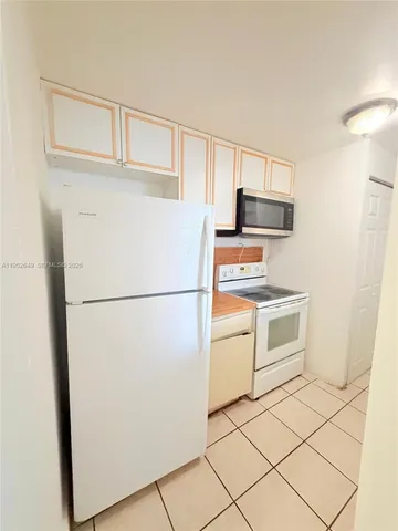 a white refrigerator freezer and a stove sitting inside of a kitchen