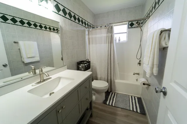 a bathroom with a sink a toilet a mirror a vanity and shower
