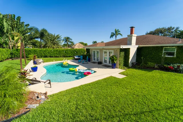 a view of backyard with table and chairs potted plants and large tree
