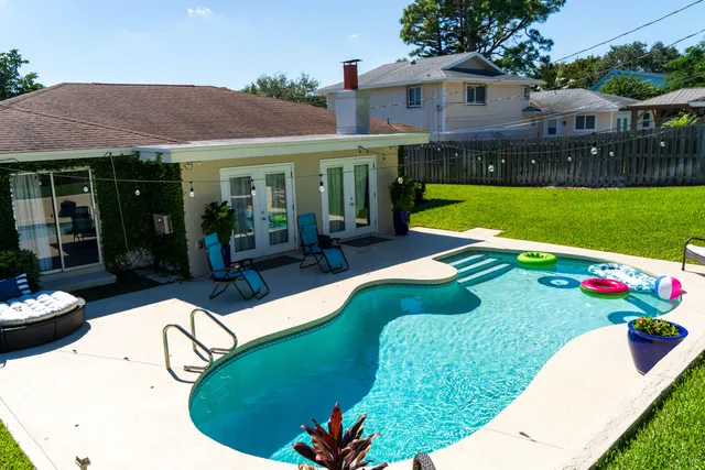 a view of a house with swimming pool lawn chairs and a yard