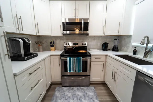a kitchen with white cabinets and black appliances