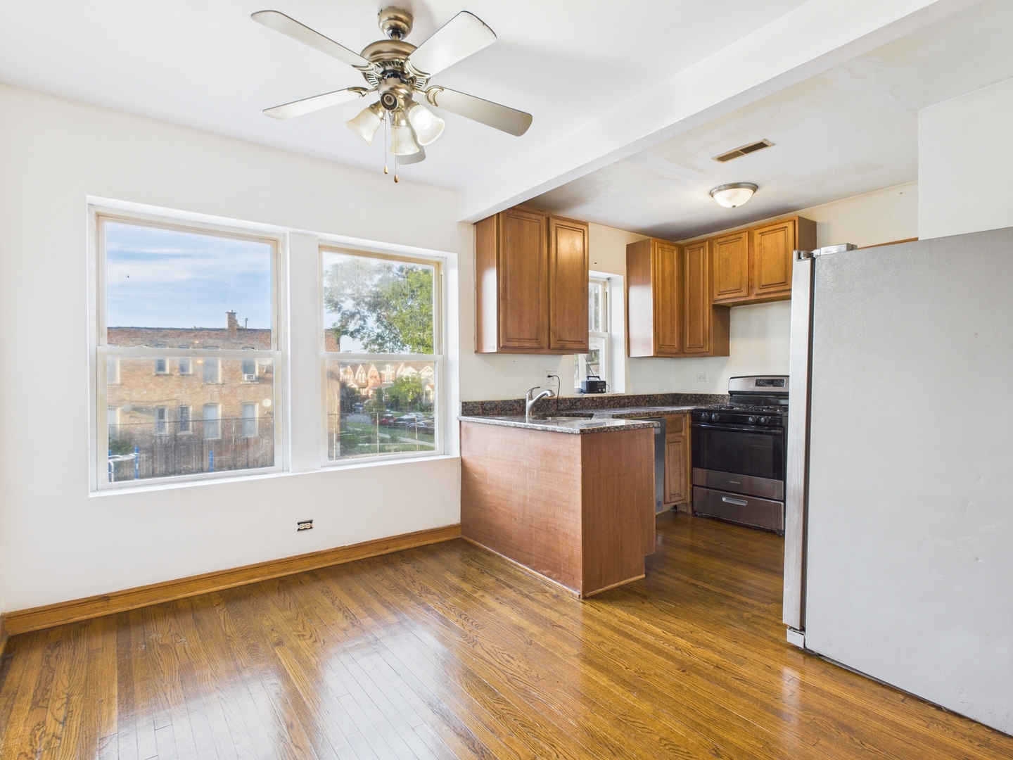 6652 South University Avenue, Unit 3B Chicago, IL 60637 - Photo 7 of 14 a kitchen with a refrigerator a stove top oven a large window with wooden floor and cabinets