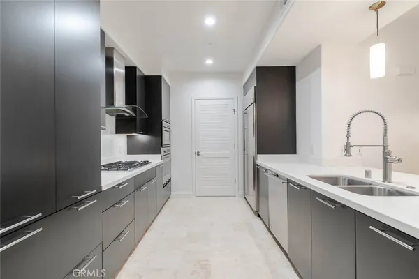 a large kitchen with a large counter top a sink stainless steel appliances and cabinets