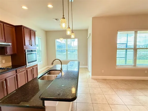 a kitchen with granite countertop a stove a sink a counter space and cabinets