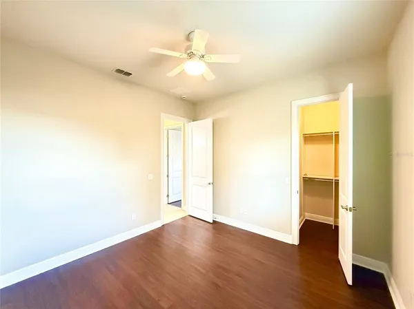 an empty room with wooden floor and a ceiling fan