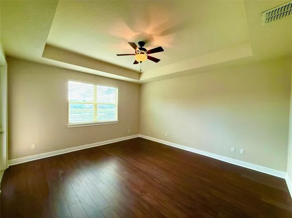 an empty room with wooden floor fan and windows