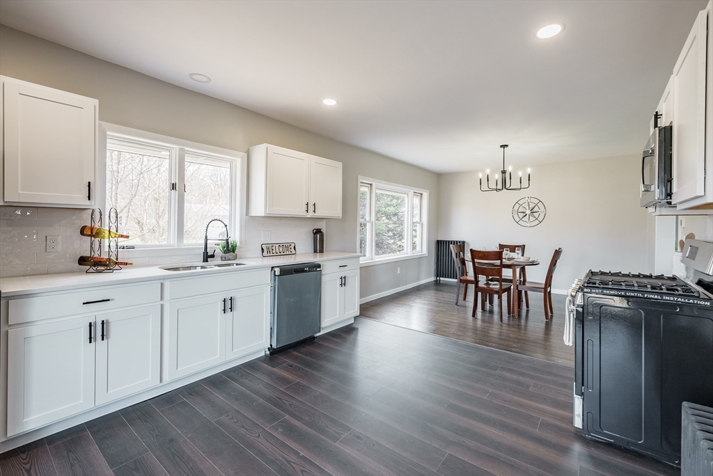 10 Bill Street Chicopee, MA 01013 - Photo 9 of 41 a open kitchen with granite countertop a stove a sink a dining table and chairs with wooden floor