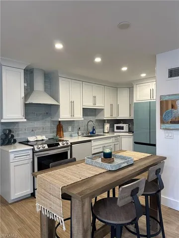 a kitchen with a stove a sink a kitchen island and chairs in it