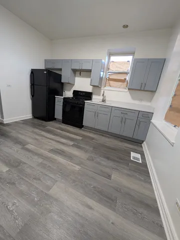 a kitchen with granite countertop a refrigerator cabinets and wooden floor