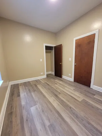 a view of an empty room with wooden floor and closet